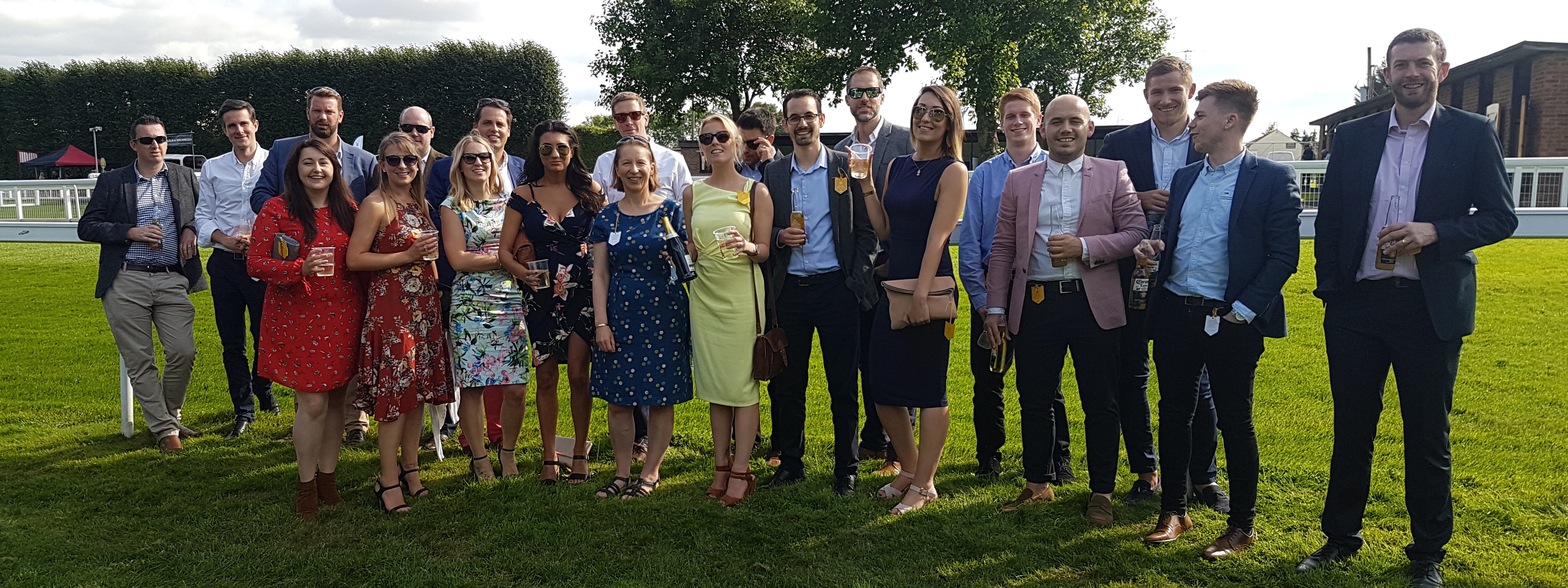 Group photo of employees of Spectrum IT standing on the grass at Salisbury Races